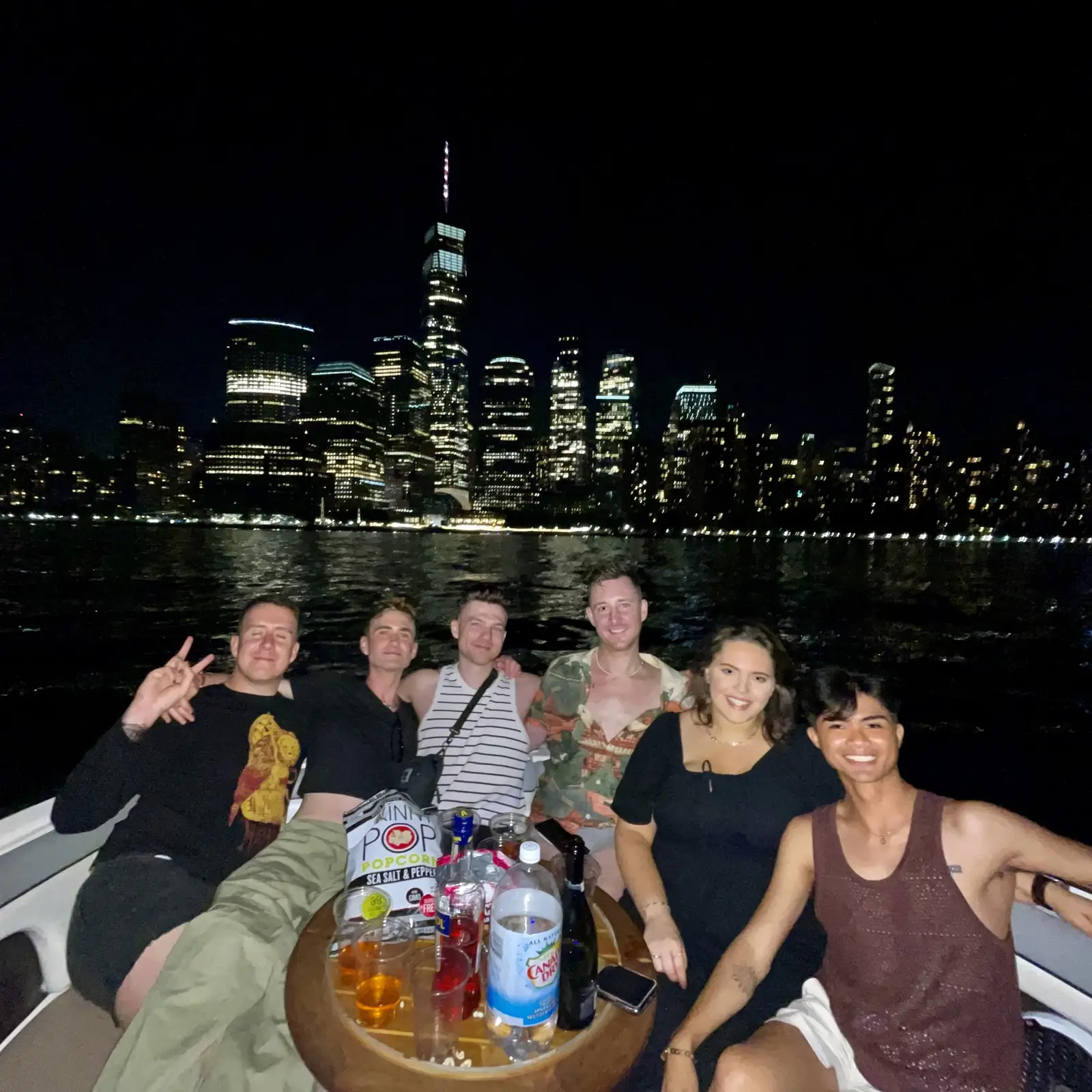 Guests enjoying the illuminated NYC skyline at night from the boat