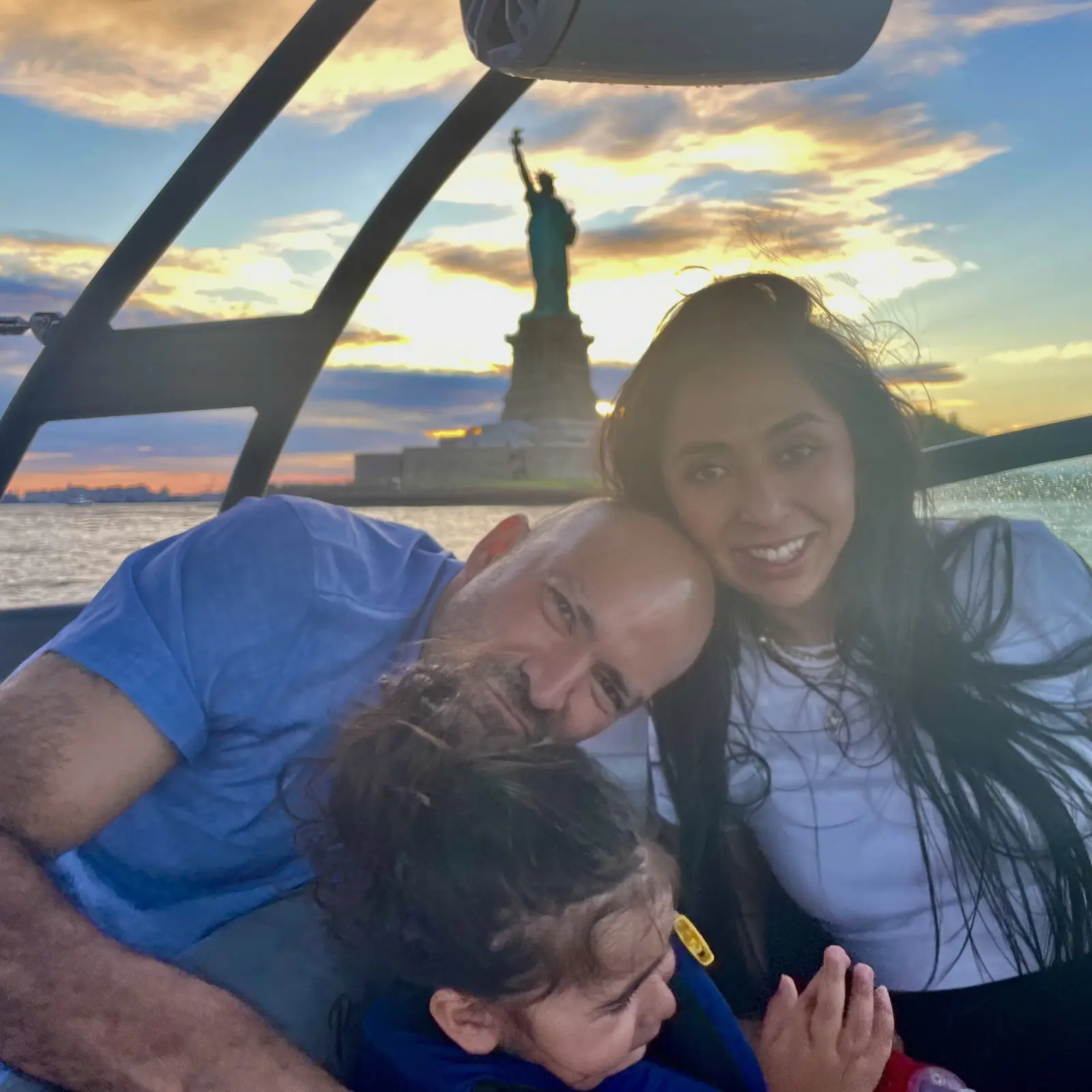 A family with a young child watching the sunset near the Statue of Liberty