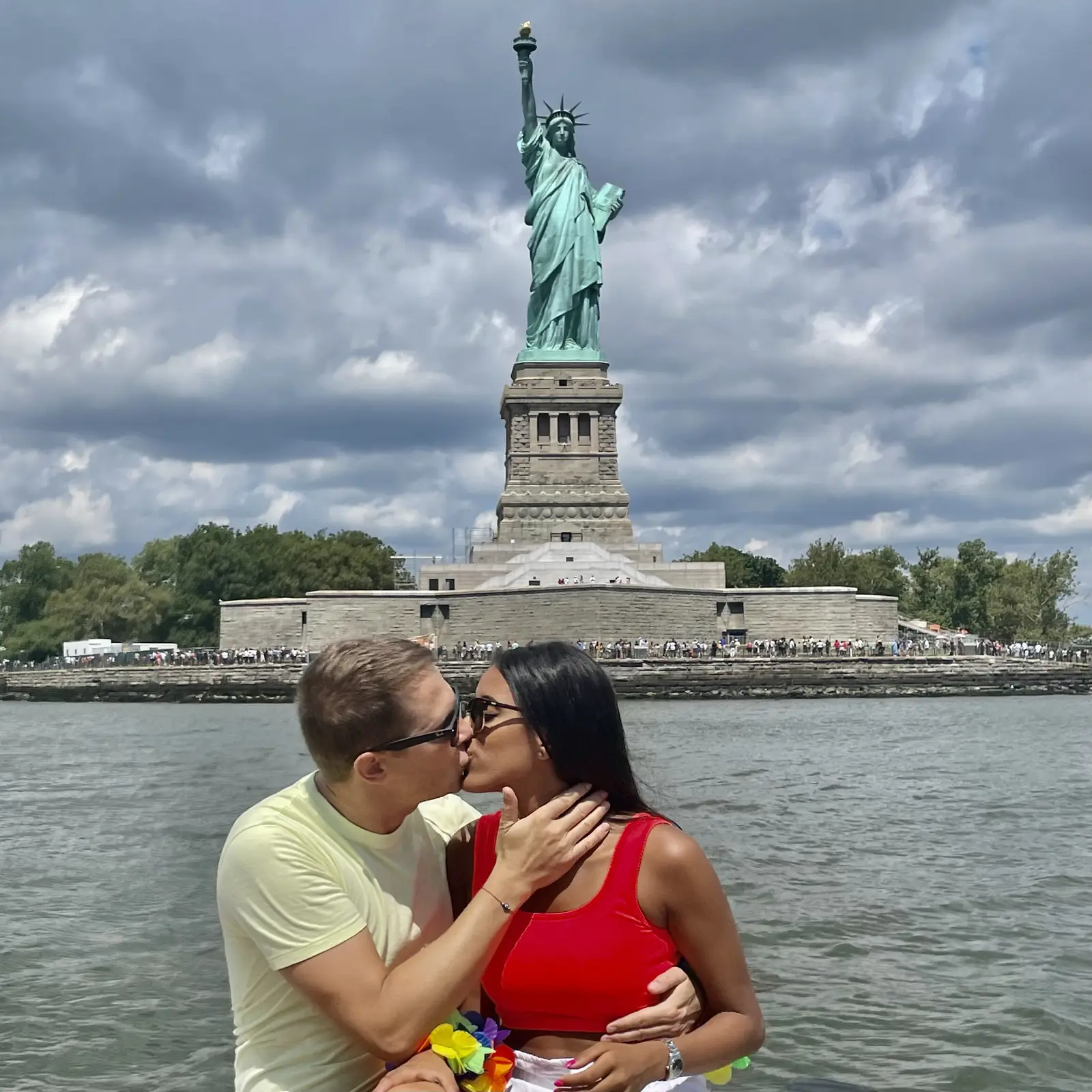 A couple sharing a kiss with the Statue of Liberty in the background