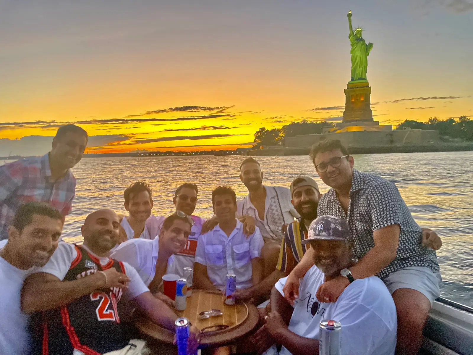 A group of friends celebrating a sunset charter near the Statue of Liberty